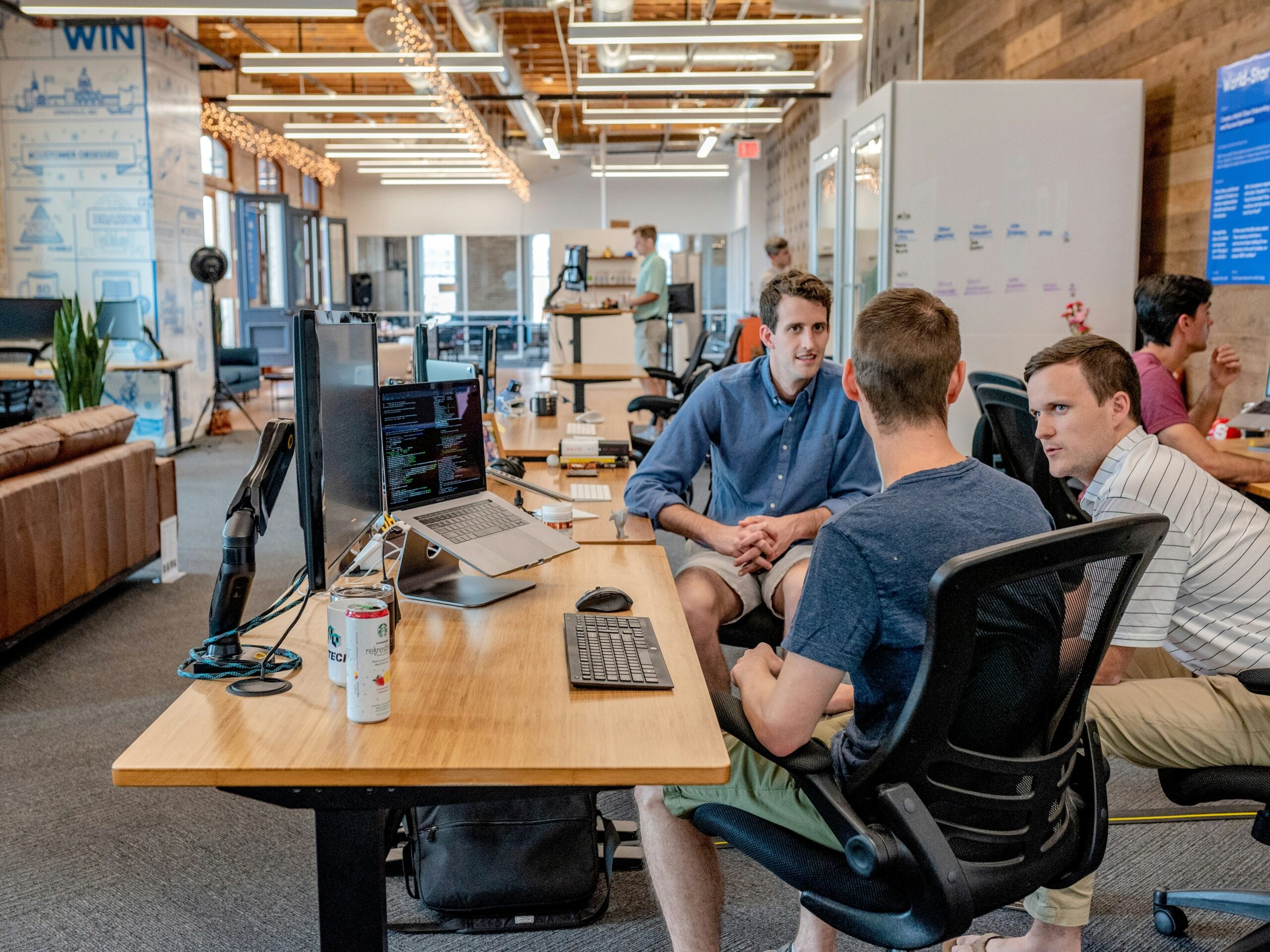 Three men sitting on chairs beside office desk